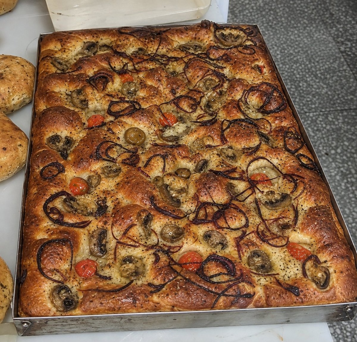 Focaccia artesana de C. Esteller con cebolla caramelizada y hierbas sobre bandeja